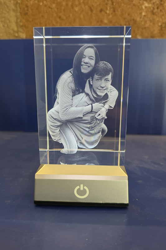 Cubo de cristal iluminado con el grabado 3D de dos personas en cococho