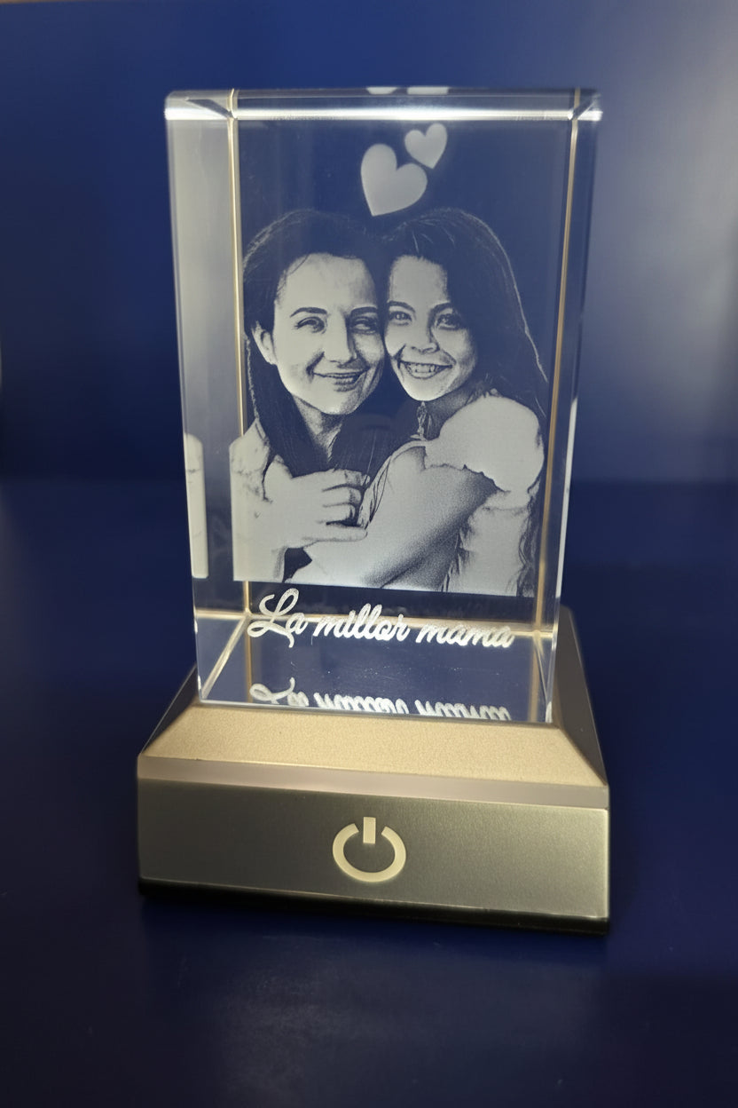 Cubo de cristal iluminado con el grabado 2D de dos personas abrazándose, corazones y la dedicatoria La millor mama