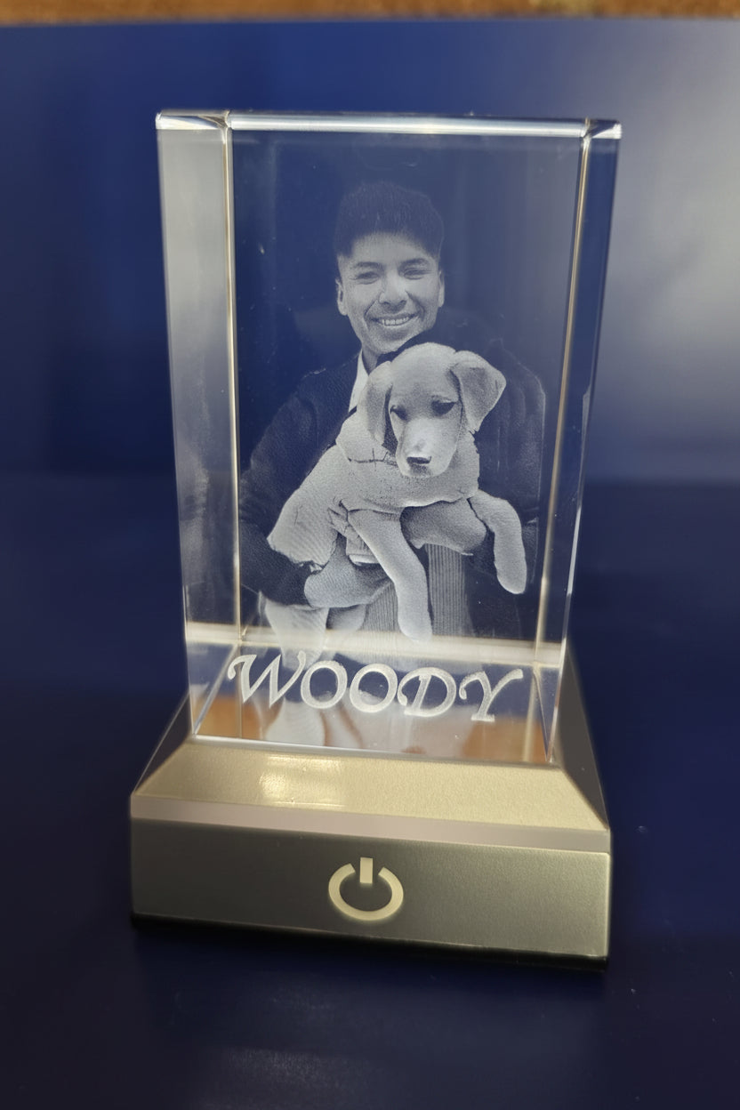 Retrato personalizado en cristal 3D de una persona abrazando a un perro cachorro, con el texto WOODY en la parte inferior